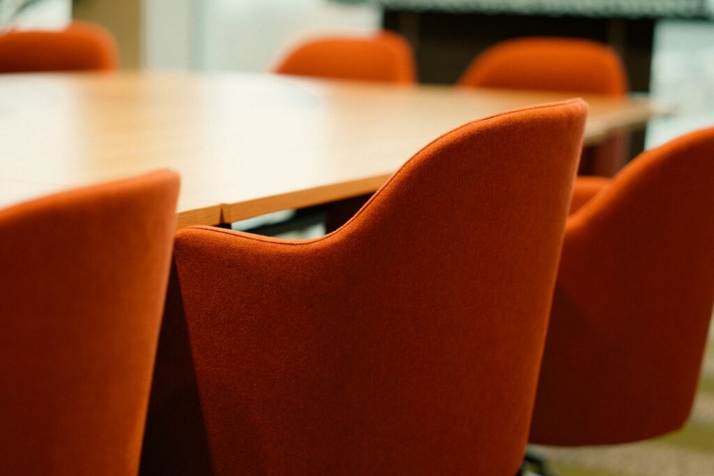 embark Close-up view of modern orange chairs around a conference table in an office setting.